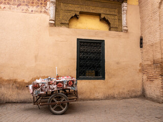 Street Vendor's Cart Adorned with Coffee Cup Patterned Cloth, Nestled Against an Ornate Historic Wall in Marrakech, Morocco