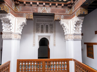 Detailed View of a Traditional Moroccan Interior in Marrakech Showcasing Elaborate Plasterwork, Carved Wood Elements, and a Decorative Balustrade