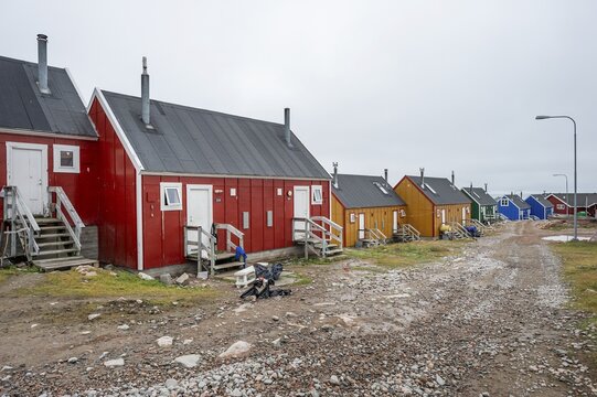 Row of colourful houses along a gravel road under a cloudy sky, remote Arctic Inuit settlement Ittoqqortoormiit, Scoresbysund or Scoresby Sund or Greenlandic Kangertittivaq, East Greenland, Greenland