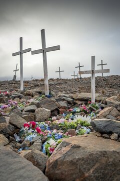 White crosses mark flower-decorated graves in a cemetery in foggy weather, remote Arctic Inuit settlement Ittoqqortoormiit, Scoresbysund or Scoresby Sund or Greenlandic Kangertittivaq, East Greenland, Greenland
