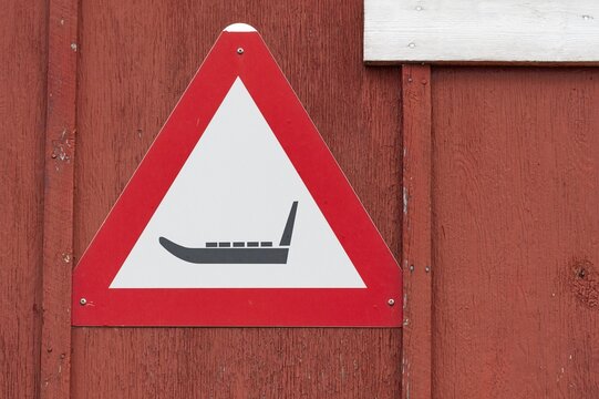 Triangular warning sign with sledge symbol on a red wooden wall, remote Arctic Inuit settlement Ittoqqortoormiit, Scoresbysund or Scoresby Sund or Greenlandic Kangertittivaq, East Greenland, Greenland