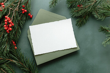 Obraz premium Overhead view of a blank card and envelope on festive Chistmas fir branches and berries 