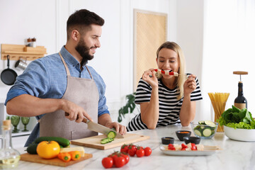 Happy couple cooking together at table in kitchen