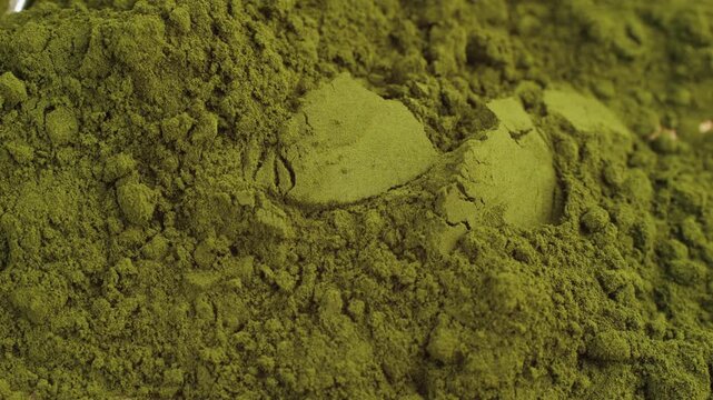 Green chlorella algae powder on a wooden spoon, top view. Healthy nutritional supplement.