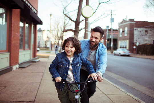Young boy learning to ride a bike with father