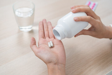 Sick asian young woman, girl holding tablet pill on hand pour capsule from medication bottle, painkiller medicine from stomach pain, headache, pain for treatment, take drug or vitamin, health care.