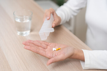 Sick asian young woman, girl holding tablet pill on hand pour capsule from medication box, painkiller medicine from stomach pain, headache, pain for treatment, take drug or vitamin, health care.