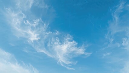 Clouds move across the tropical sky during daytime, featuring white and blue colors with semi-transparent layers at different heights. Time lapse.
