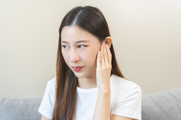 Fototapeta premium Tinnitus concept, sick asian young woman, girl have ear pain or earache, hand touch plug ear, suffering painful otitis from loud of noisy sound, inflammation. Health care nerve deaf eardrum disease.