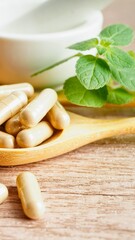 Natural herbal supplements on a wooden spoon with fresh mint leaves