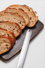 Close up of bread knife on wooden cutting board with sliced whole wheat sourdough bread