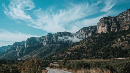 Bluffs Across The Road with mountain cliffs and forested landscape under a blue sky with scattered clouds.