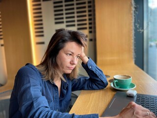 Close up of Caucasian upset businesswoman sitting in cafe working on laptop looking at screen with sad face. Female freelancer with unhappy face typing on computer. Freelance work