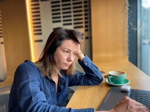 Close up of Caucasian upset businesswoman sitting in cafe working on laptop looking at screen with sad face. Female freelancer with unhappy face typing on computer. Freelance work - Powered by Adobe