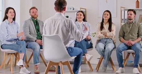Group of positive people sitting in a circle, engaging in a group psychotherapy session. Talking together with a psychologist, seeking support and help. Togetherness in a therapeutic setting.