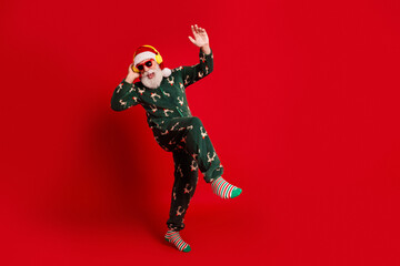 Dancing Santa in festive pajamas wears headphones and striped socks against a bold red background for christmas fun