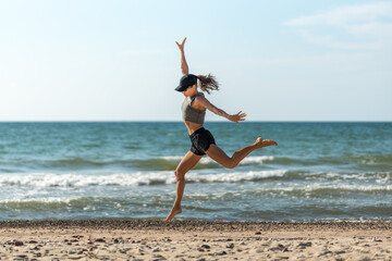 Dynamic female athlete on sunny shoreline, Cheerful woman in energetic motion leaping at coast with windblown hair