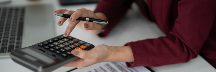 Adult hands calculating property finances using a calculator for real estate sales agent mortgage planning at office desk professional budgeting