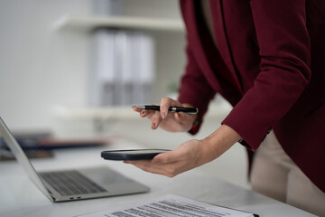 Fototapeta premium Adult real estate agent manages property listings digital contracts with pen mobile device laptop professional office workspace