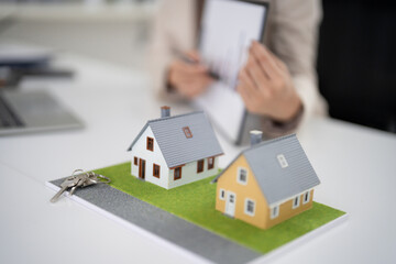 Real estate salesperson presents house models keys property options home buyers office discusses...