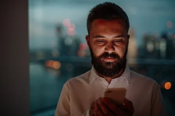 Gardinen Musik Businessman texting on smartphone, standing by window.  © Halfpoint