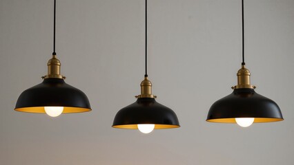 Three lighted lamps hanging from the ceiling with black and gold bases, white bulbs, and black cords.