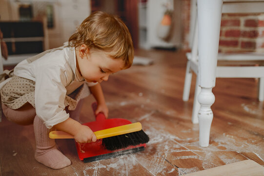 Little girl cleaning up flour mess in kitchen.