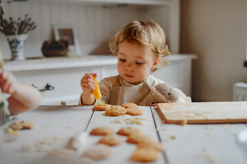 Happy children decorating Christmas cookies at home.