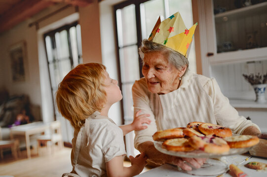 Grandmother in paper crown receiving kiss from grandchild.