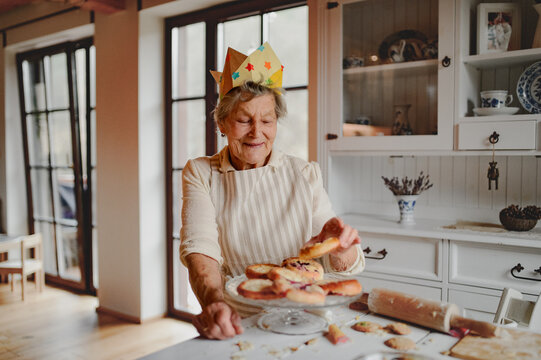 Grandmother with paper crown on head in kitchen.
