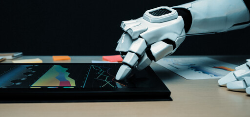 A robotic arm demonstrates interaction with a digital tablet featuring various analytical graphs, illustrating a blend of technology and innovation in a modern workspace.Noogenesis
