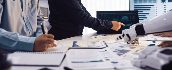 A dynamic workspace shows business professionals analyzing data on screens with advanced technology. The team discusses strategies and innovative solutions for business growth.Noogenesis