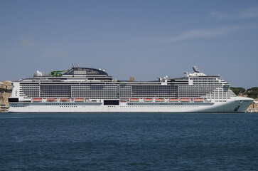 Massive mega Italian family cruiseship cruise ship Grandiosa, Bellissima Meraviglia in Valletta during Summer Mediterranean cruising in sleek modern design with port infrasctructure and marine traffic