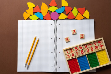 Educational materials for teaching math and shapes with colorful geometric pieces arranged on a notebook in a classroom setting