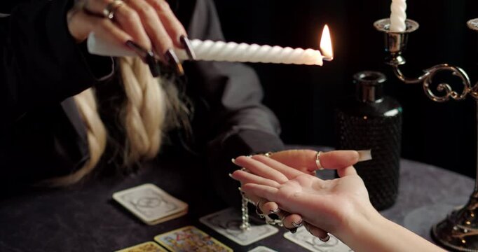 Witch using burning candle in mystical palm reading ritual
