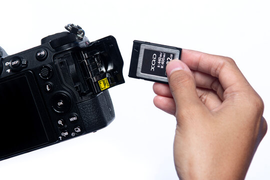Karawang, West Java - October 27 2025 : hand holding XQD or mirrorless camera memory into the slot