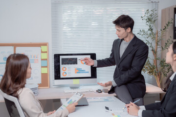 Business professionals are having a meeting in a modern office, analyzing financial data and growth charts on a computer monitor, discussing strategic planning and market trends