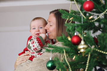 Portrait of mom and her newborn by the Christmas tree.