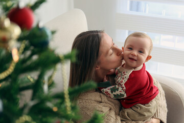 Mother with her baby by the Christmas tree.