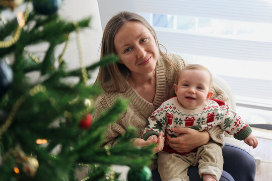 Mother with her baby by the Christmas tree.