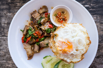 Crispy pork basil rice with fried egg, spicy food, in a round plate. Local street food style. Thai local food style