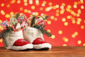 Saint Nicholas day. Boots with treats and festive decor on wooden table against blurred lights....