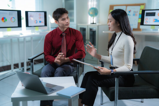Two business professionals are having a serious discussion, analyzing data and information displayed on computer monitors in a modern office environment