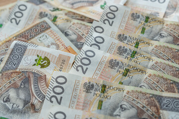 Close up of 200 Polish zloty banknotes spread out on table, cash background and financial business concept
