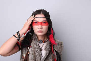Shaman woman with face painting on light grey background, space for text