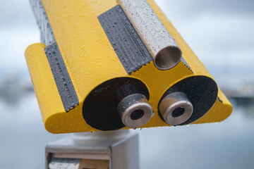 Coin operated yellow binocular viewer on blurred background of seascape, selective focus