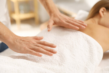 Reiki master healing patient's aura during therapy indoors, closeup