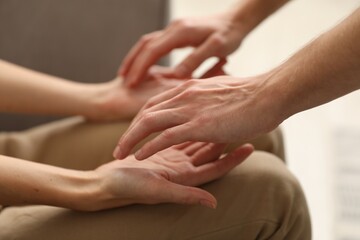 Reiki master healing patient's aura during therapy indoors, closeup