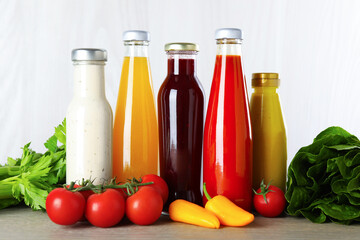Bottles of different tasty sauces and products on grey wooden table, closeup