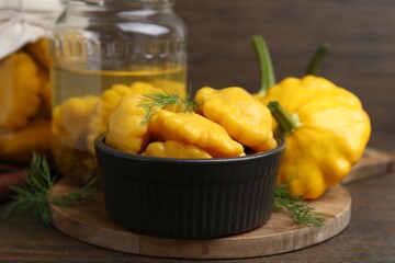 Pickled pattypan squashes and dill on wooden table, closeup